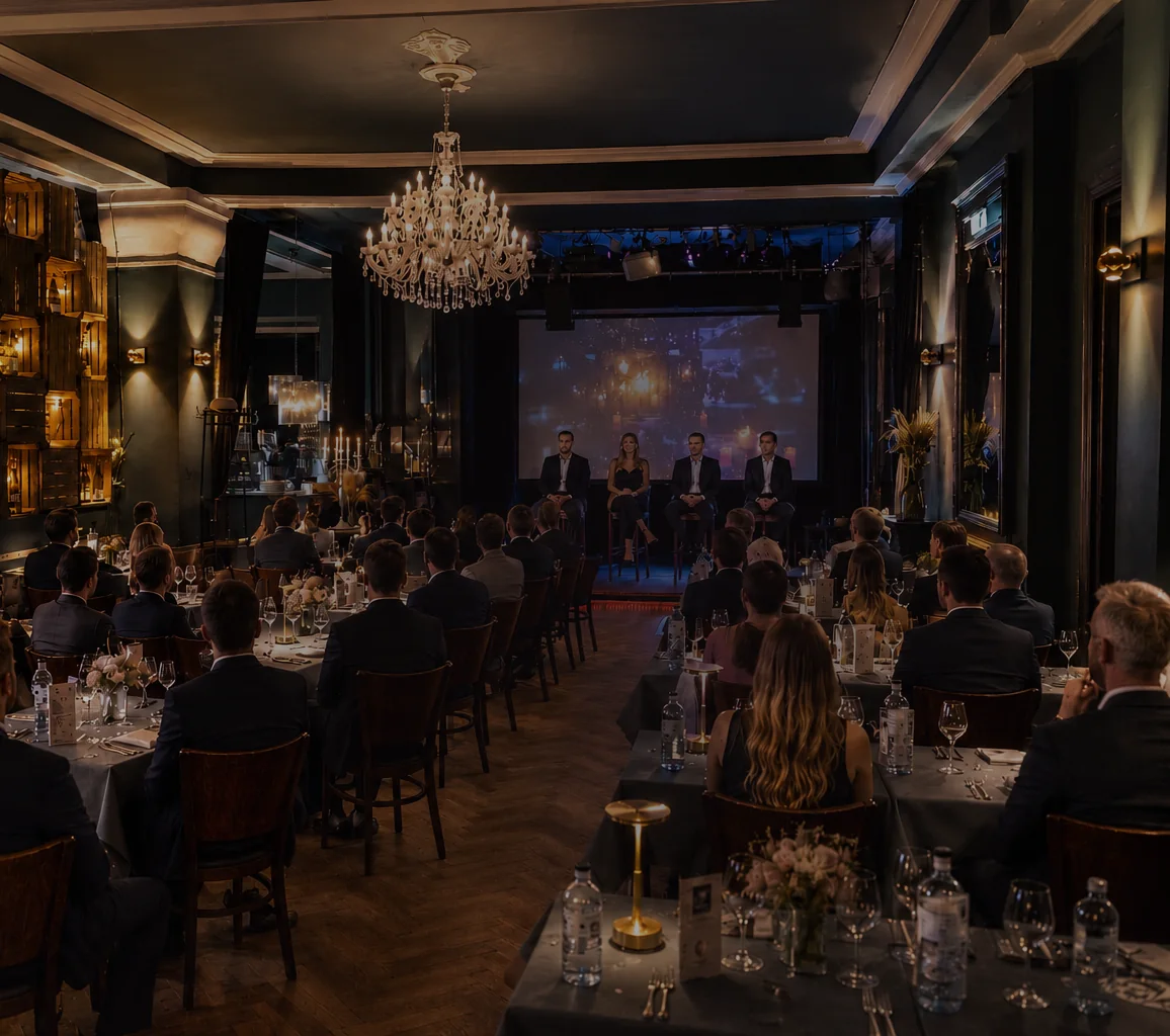 Firmenevent im Vorwerck Event Restaurant in Berlin, Podiumsrunde auf der Bühne vor Gästen an gedeckten Tischen